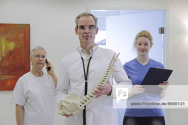 A doctor and his team describing back pain with a model