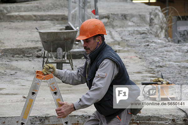 Bauarbeiter klettert auf eine Betonplatte um zu arbeiten