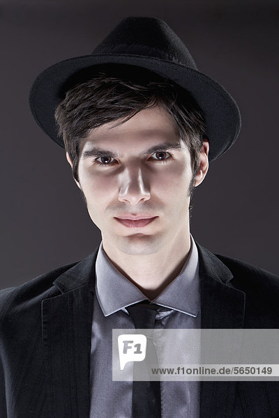 Junger Mann im schwarzen Anzug mit Hut  Portrait