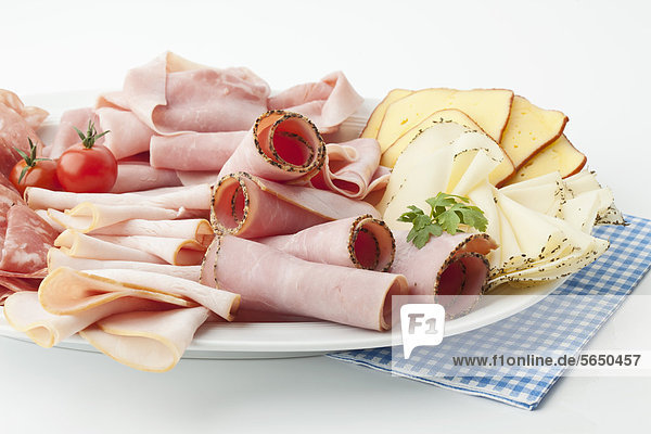 Verschiedene Fleisch- und Käsescheiben im Teller auf weißem Hintergrund