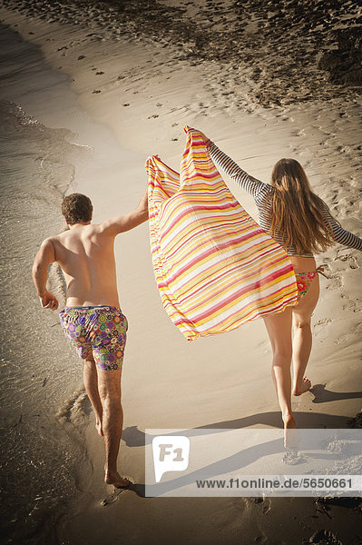 Spanien  Mallorca  Paar läuft am Strand entlang