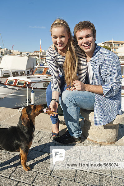 Spanien  Mallorca  Paar Fütterung Eis an streunenden Hund  lächelnd  Portrait