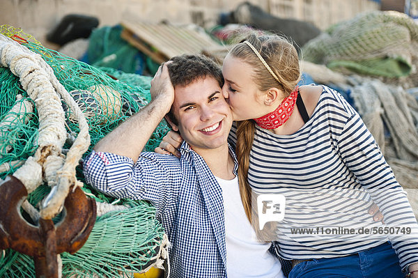 Spanien  Mallorca  Paar am Hafen mit Fischernetzen  lächelnd