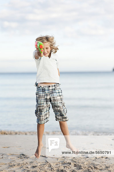 Spanien  Mallorca  Junge mit Wasserpistole am Strand  Portrait