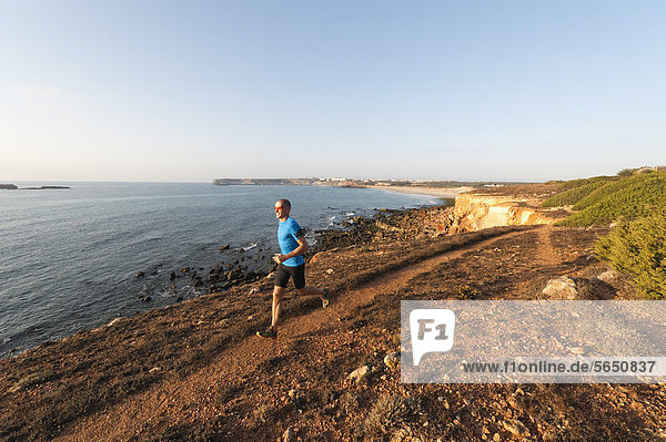 Portugal Algarve  Mature man jogging by coast
