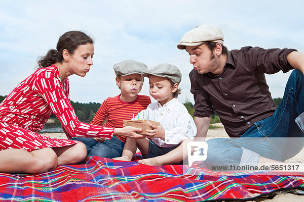 Junge und Familie mit Geburtstagstorte auf Picknickdecke