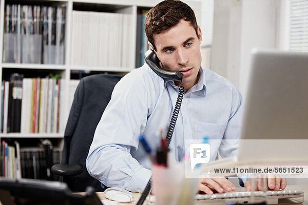 Young man on telephone and working on laptop