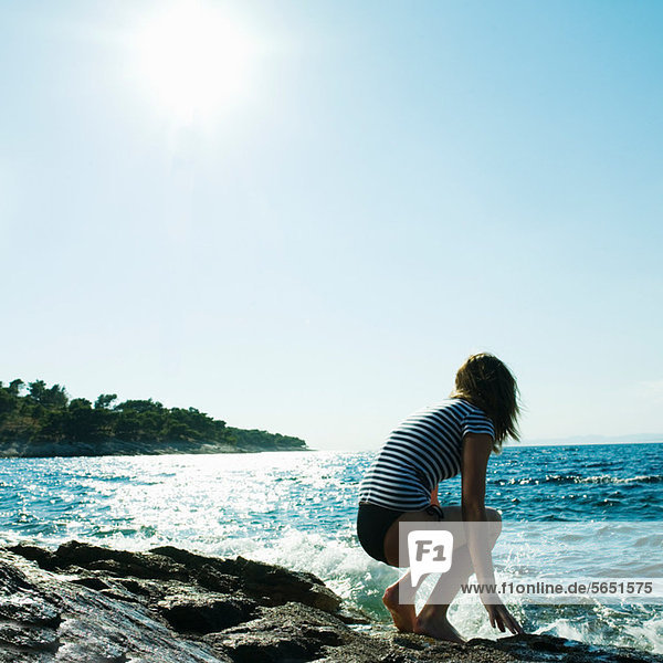 Young woman crouching by the sea
