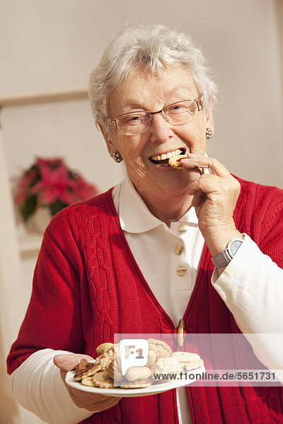 Senior woman eating christmas cookies  portrait