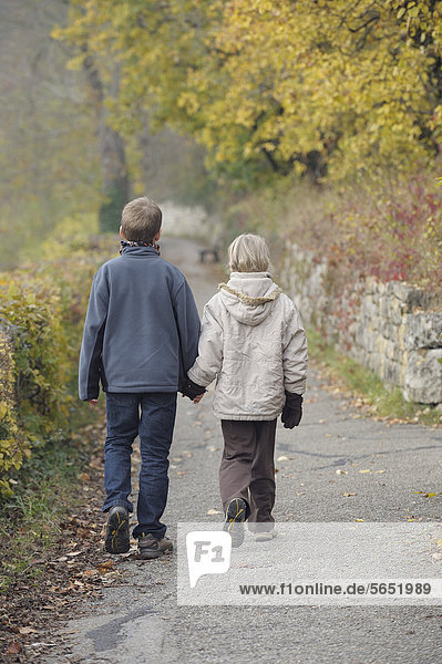 Deutschland  Bayern  Geschwister wandern im Herbst auf dem Wanderweg