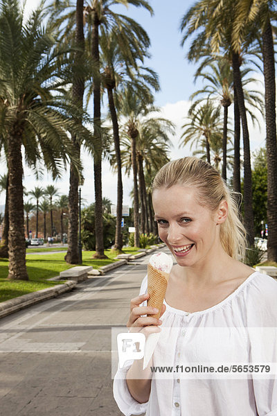 Spain  Mallorca  Palma  Young woman eating ice cream  smiling  portrait