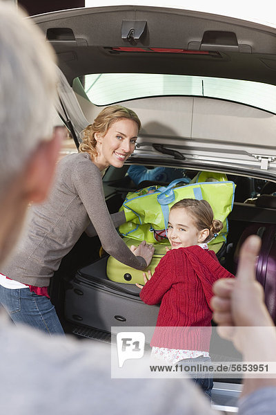 Deutschland  Leipzig  Familie beim Verladen von Gepäck ins Auto  lächelnd