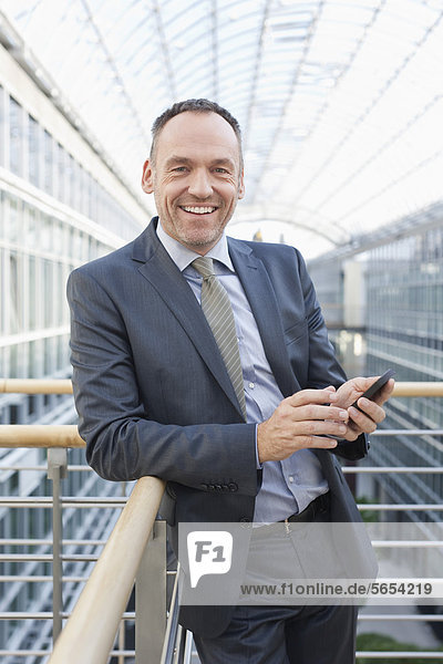 Deutschland  Leipzig  Geschäftsmann mit Handy  lächelnd  Portrait
