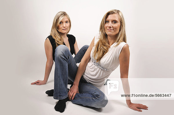 Twin sisters sitting on the floor
