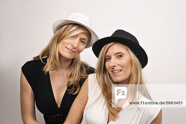 Twin sisters wearing hats in black and white in opposite colors to their clothes