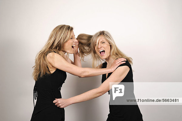 Zwillingsschwestern streiten und ziehen sich dabei gegenseitig an den Haaren