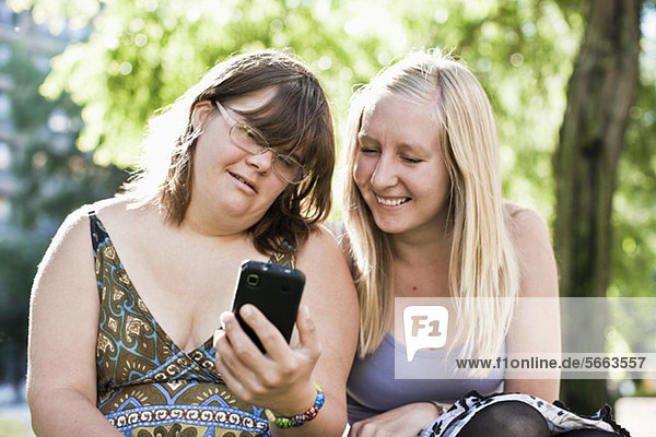 Junge Frau mit Down-Syndrom ihre persönliche Assistentin beim gemeinsamen Telefonieren