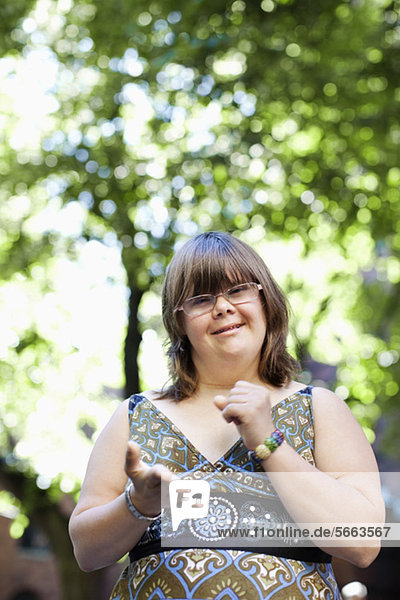 Porträt einer jungen Frau mit Down-Syndrom  die ihre Faust in Gebärdensprache zusammendrückt