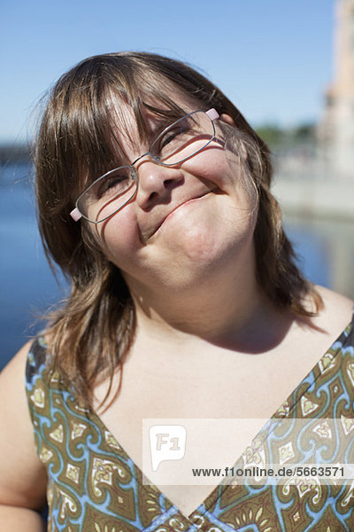 Close-up portrait of cute woman with down syndrome smiling outdoors
