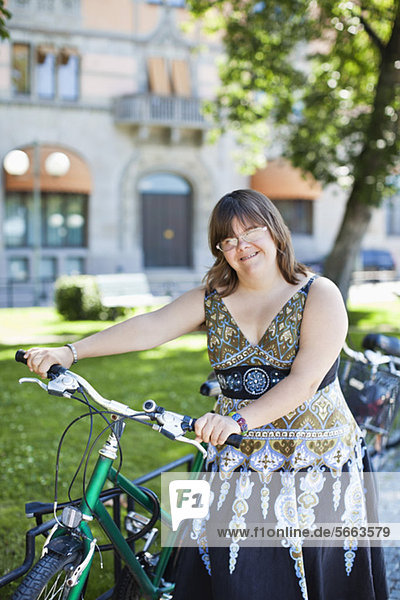 Portrait einer jungen Frau mit Down-Syndrom lächelnd mit Fahrrad