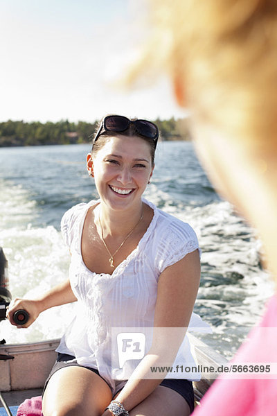 Lächelnde Frau  die ihren Freund auf dem Motorboot ansieht.