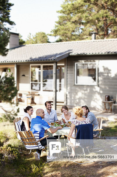 Group of friends enjoying while sitting together in front of house