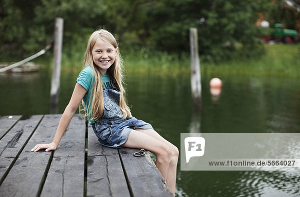Porträt eines lächelnden blonden Mädchens am Pier im See