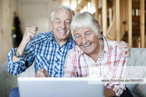 Aufgeregtes Seniorenpaar beim Betrachten des Laptops