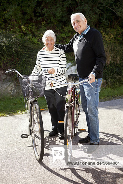 Portrait of active senior couple standing together with bicycles