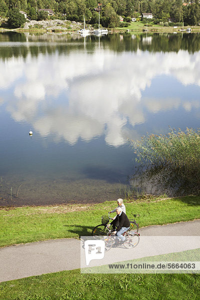 Hochwinkelansicht des Seniorenpaares beim Radfahren am See