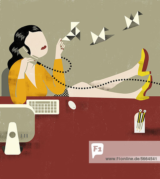 Geschäftsfrau macht Origami-Vögel am Schreibtisch während sie telefoniert