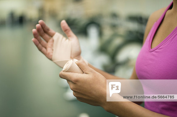 Frau umwickelt Hand mit Verband,  beschnitten