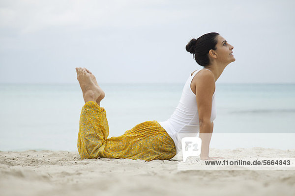 Reife Frau beim Yoga am Strand  Seitenansicht
