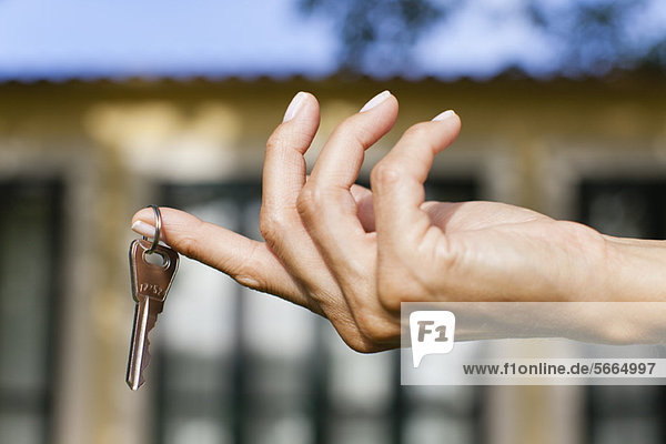 Frauenhand hält Schlüssel  abgeschnitten