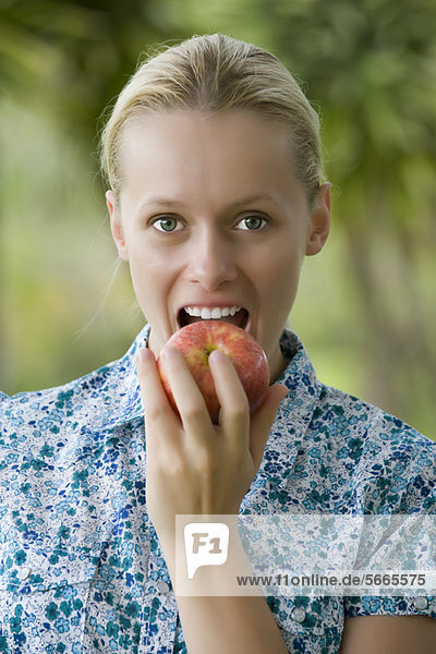 Junge Frau beißt in den Apfel  Portrait