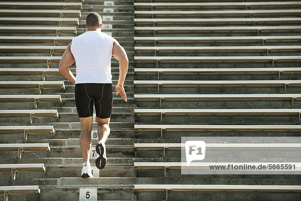 Mann läuft im Stadion die Treppe hoch  Rückansicht