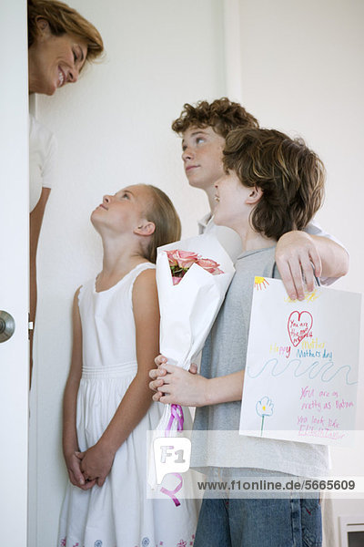 Kinder schenken Mutter Blumen und handgemachte Grußkarte