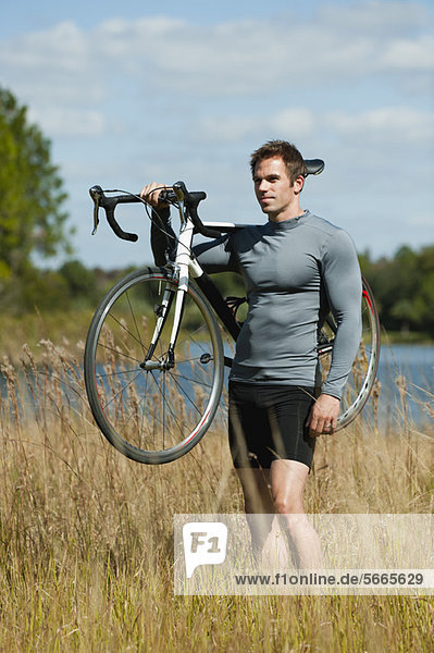 Man carrying bicycle on shoulder in nature  portrait