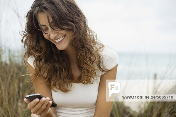 Lächelnde junge Frau beim Anblick des Handys