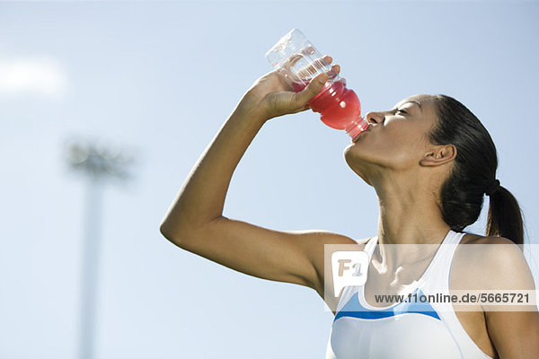 Young female athlete drinking sports drink  portrait
