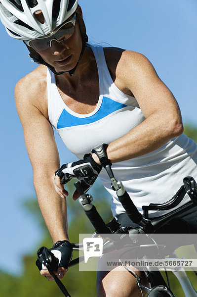 Female cyclist monitoring heart rate on wristwatch