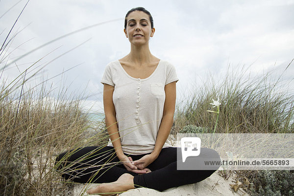 Lächelnde reife Frau beim Meditieren am Strand  Portrait