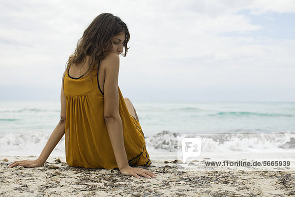 Junge Frau am Strand sitzend