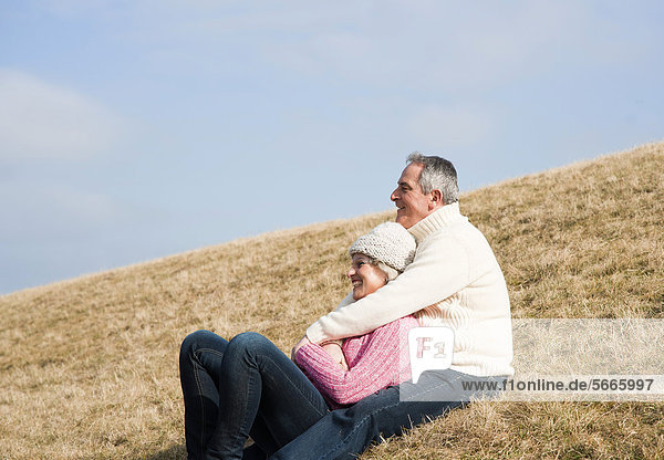 Smiling couple sitting in meadow