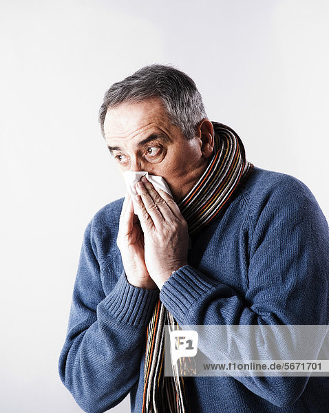 Senior in Winterkleidung putzt sich die Nase