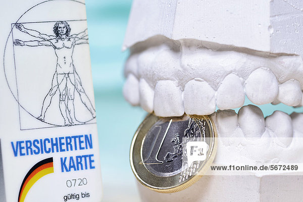 Versichertenkarte  Zahn-Gipsabdruck und Ein-Euro-Münze  Symbolbild stärkere Kontrollen von Zahnarztabrechnungen durch Krankenkassen