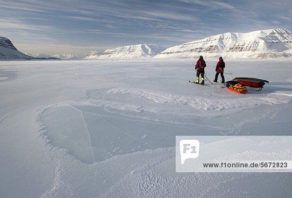 Cross-country skiers with pulkas crossing a frozen fjord  Tempelfjorden  Spitsbergen  Svalbard  Norway  Europe