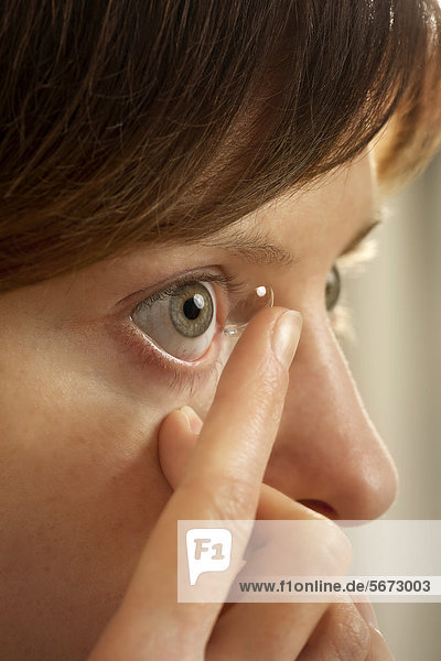 Frau beim Einsetzen einer Kontaktlinse