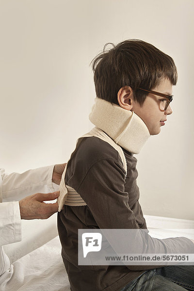 Boy wearing a cervical support being examined by a pediatrician  whiplash