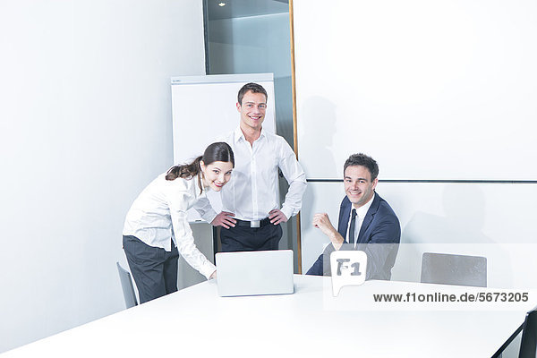 Three business people working on laptop in conference room